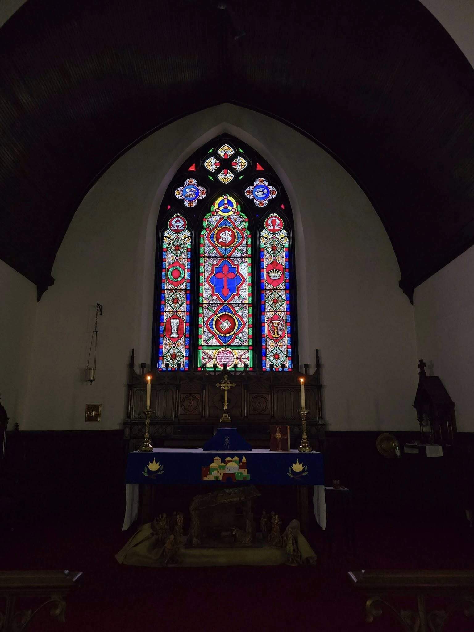 A group of people in a church sing hymns. Stained glass windows and decorative columns create a serene atmosphere.